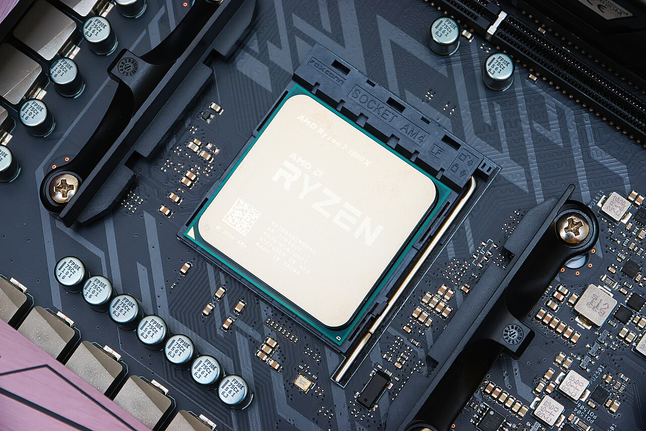 Makroaufnahme eines Prozessors im Sockel eines Mainboards, ringsum Kondensatoren und Spannungswandler